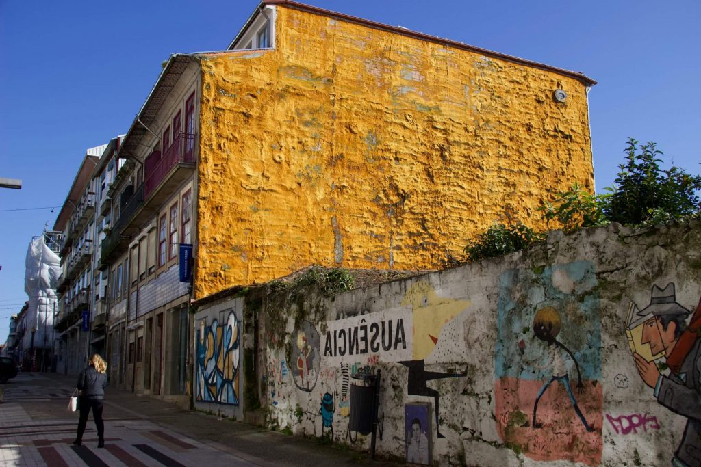 在波尔图，街头艺术、涂鸦和一名女子走过一栋亮黄色的建筑。©开云体育登录入口手机版官网网址KettiWilhelm2020