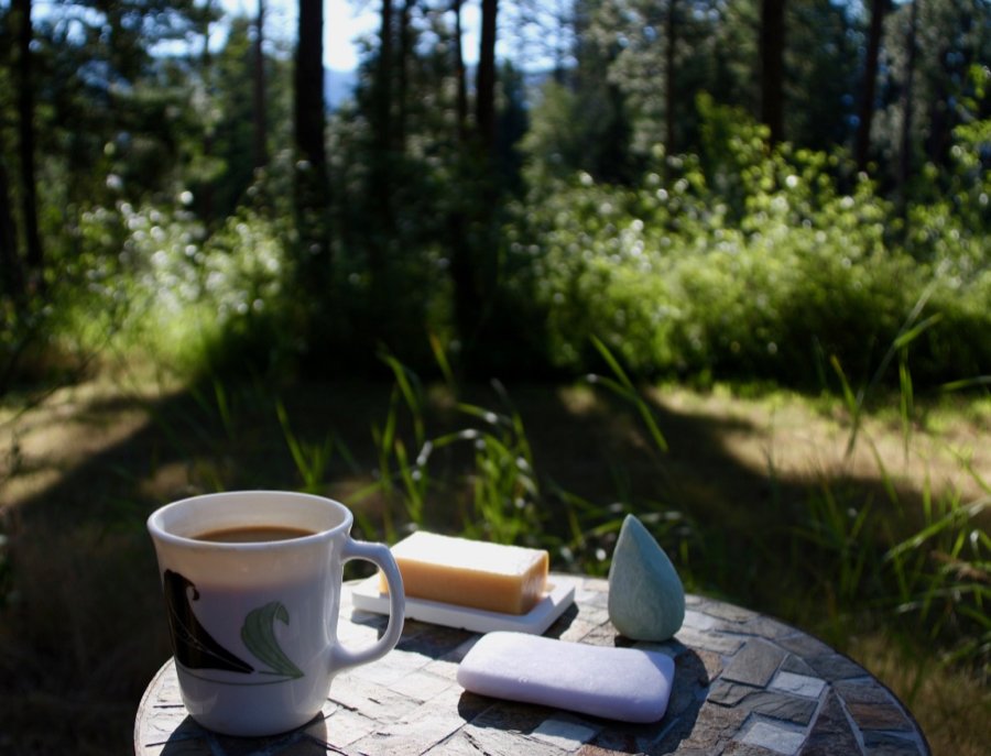 在外面的桌子上喝一杯咖啡，旁边是3个零废物洗发水，拍摄照片，背景是森林。©开云体育登录入口手机版官网网址KettiWilhelm