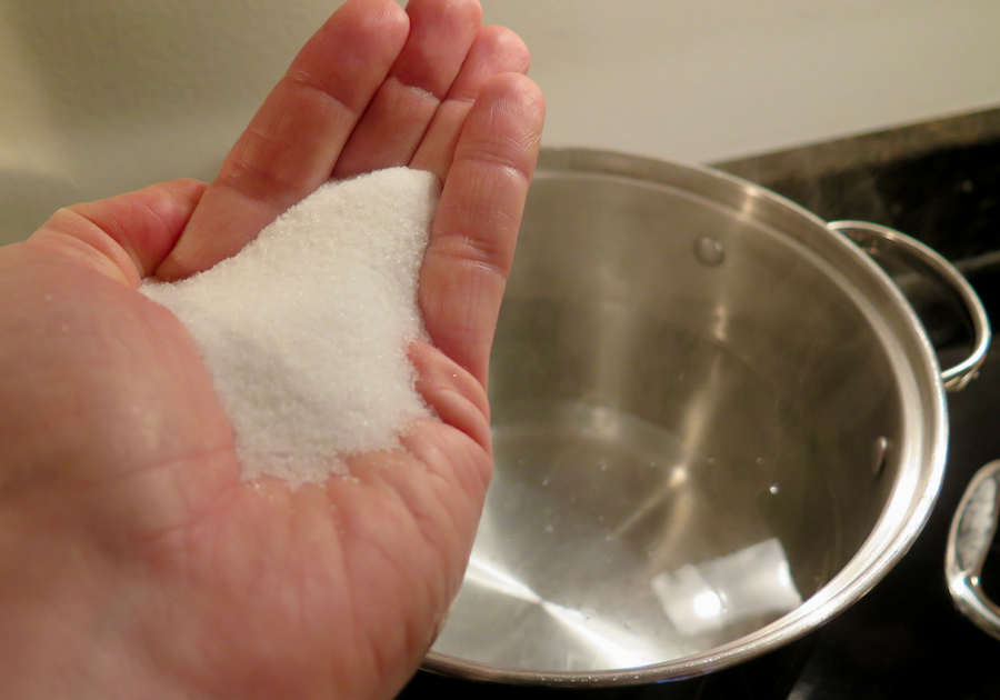 把一把盐倒在煮意大利面的水里(背景是锅里的水)。©开云体育登录入口手机版官网网址KettiWilhelm2021