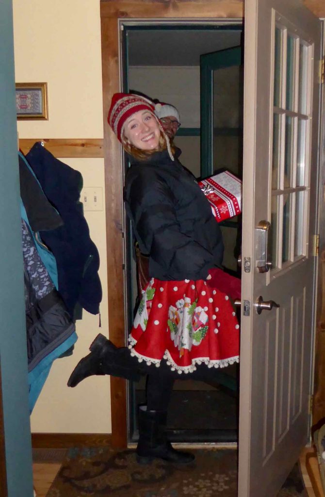 这本可持续的礼物指南的作者，在门口穿着圣诞树的裙子作为真正的裙子，并携带包装好的礼物。©开云体育登录入口手机版官网网址KettiWilhelm2021