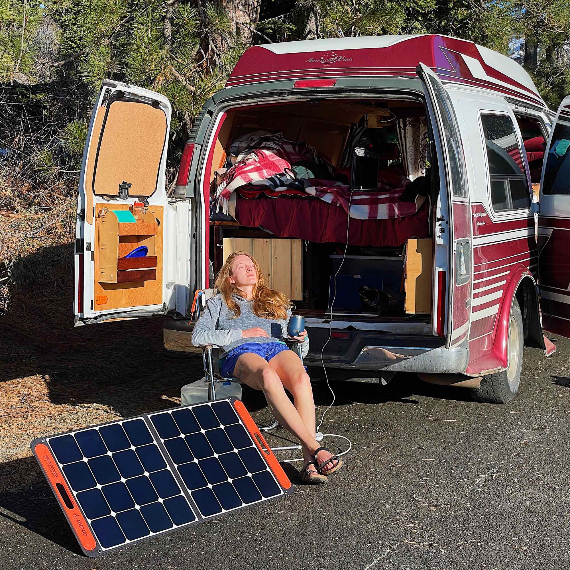 作者坐在阳光下的折叠椅上，旁边是她的Jackery太阳能电池板和改装的面包车。©开云体育登录入口手机版官网网址KettiWilhelm2021