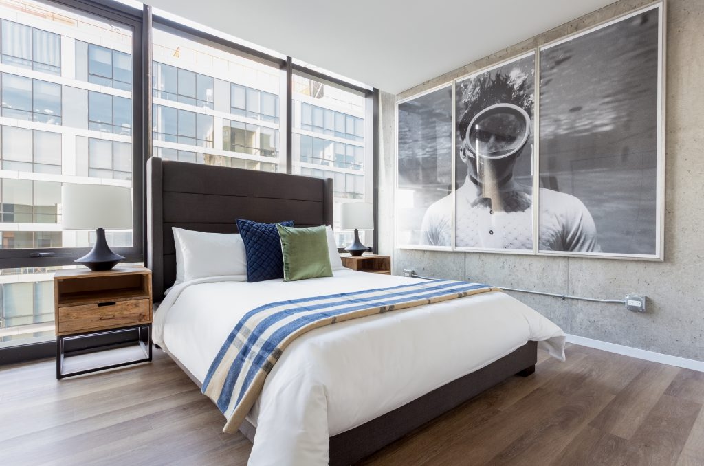 芝加哥Sonder公寓的一间时髦宽敞的卧室，床旁有一张很大的黑白照片，落地窗也有。