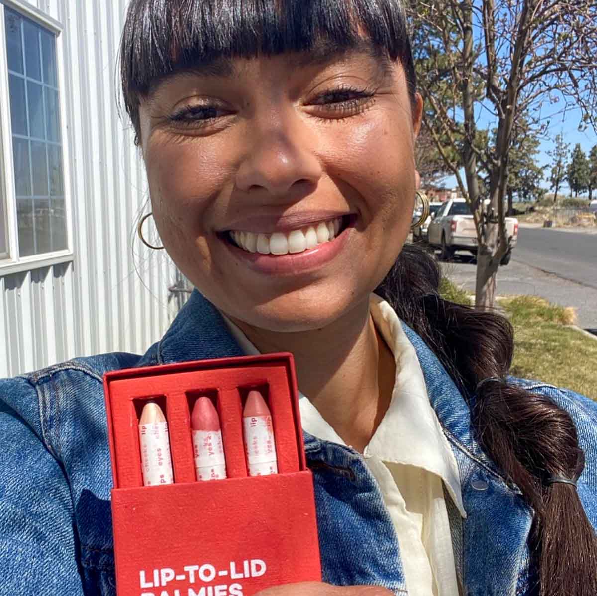 Ericka是一家可持续发展的小型美容公司Axiology的创始人，她在街上微笑着自拍，手里拿着她的产品。